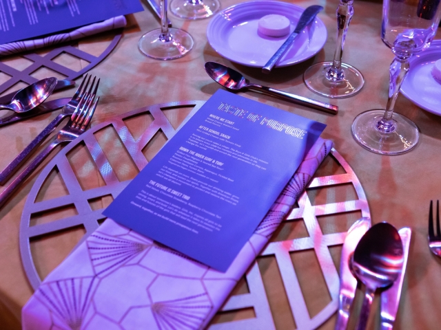 Table setting including silver charger plate with navy menu and napkin.