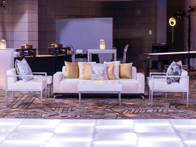 Lounge area next to dance floor with white couches and sequence pillow.