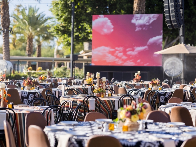 A view of multiple tables with floral centerpieces and patterned table cloth.