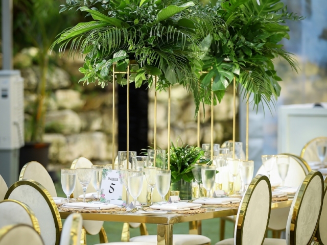 White and gold table arrangement with large foilage centerpiece for incentive trip dinner in Bahamas.