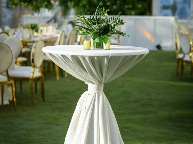 High top table with white table cloth, small foilage centerpiece, and candles for incentive trip dinner in Bahamas.