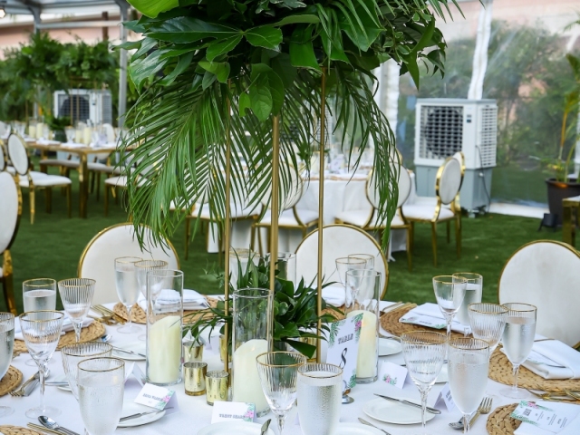 A close view of a table setting with floral-design menu, round woven placemat, and large foilage centerpiece.