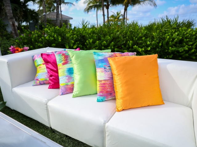 White couch with colorful pillows for Junkanoo theme.