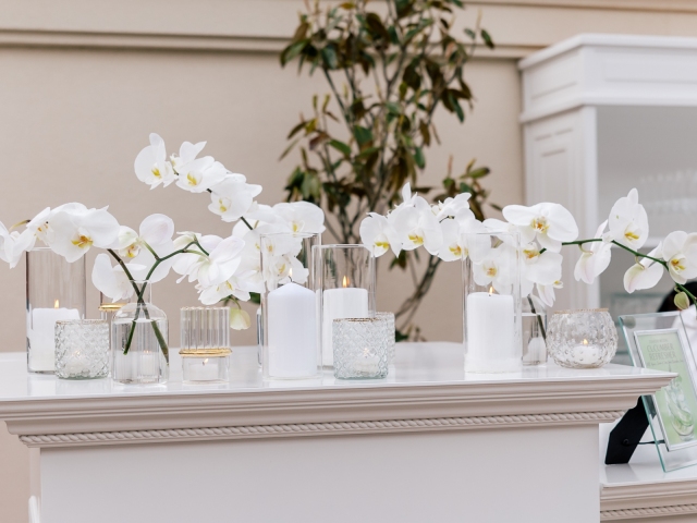 White floral display on the bar of a white party event.