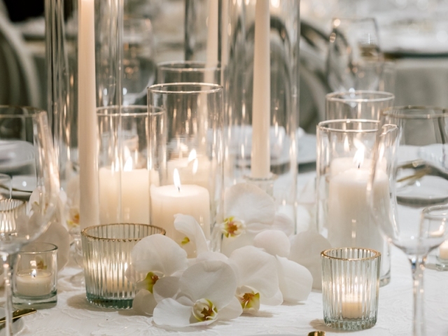 White elegant candles of different sizes on dinner table.