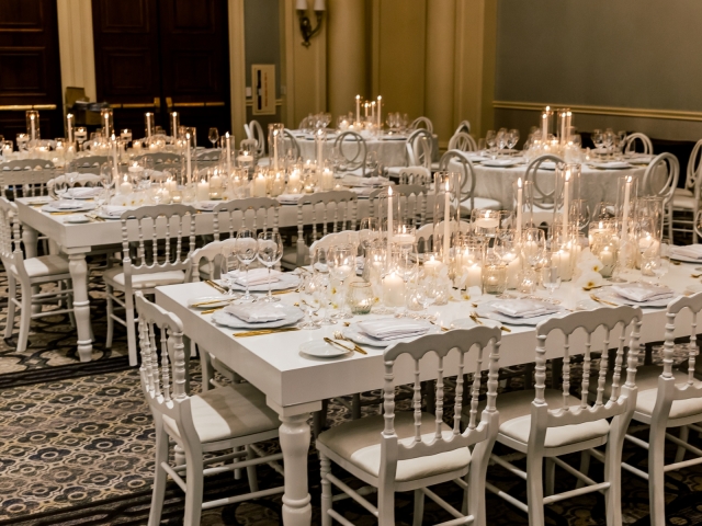 Long tables white wooden tables with white chairs and white table settings with white candle display.