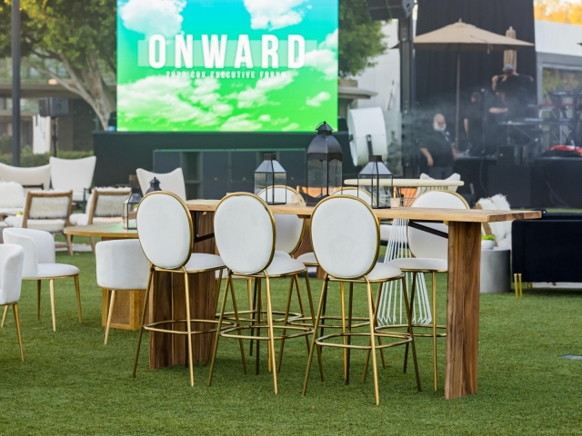 High top table with white and gold chairs with view of presenter screen.