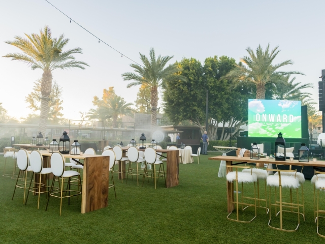 High top tables with view of palm trees and screen.