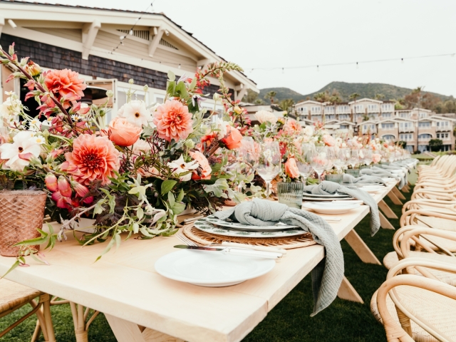 Close up of long rustic table and large floral centerpiece stretched across the entire table.