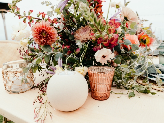 Variety of flowers and foilage on a table with candles.