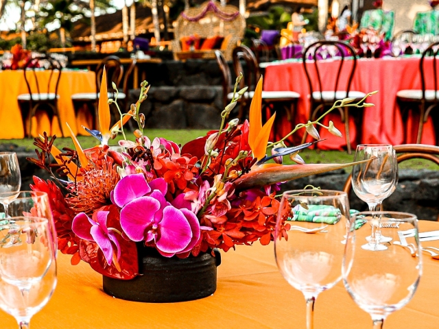 Bright floral centerpiece on round table with yellow tablecloth.