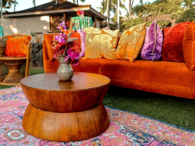 Lounge area with orange velvet couch and vibrant pillows.