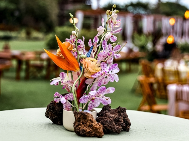 Hawaiian flowers with stones on a table.