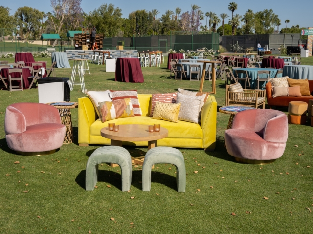 Lounge area with velvet yellow couches and pink chairs.