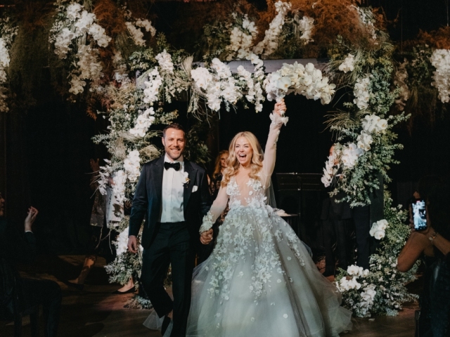 Bride and Groom celebrating under floral archway at Philadelphia wedding