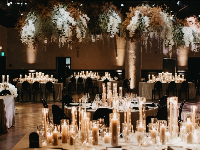 Full view of wedding with floral ceiling decor, tables with white candles.