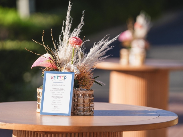 Flower and feather centerpiece on a round table with cocktail menu.