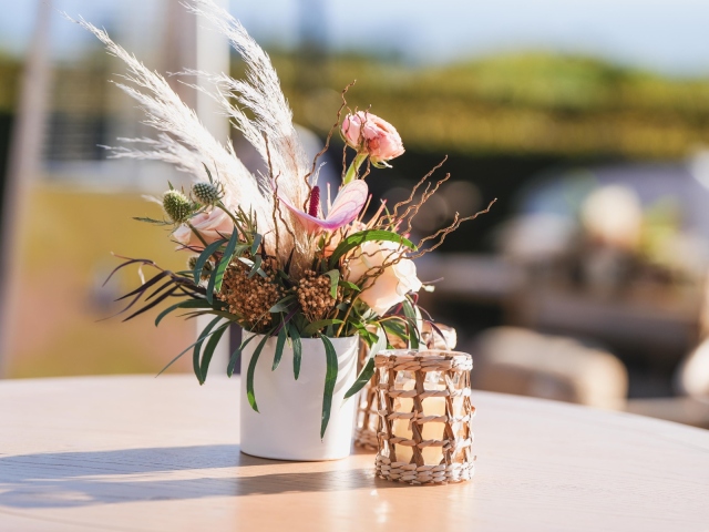 Feathered centerpiece with flowers in white pot on small circular table.