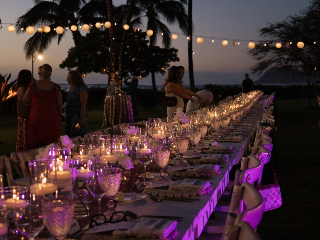 Long wooden table at night with lantern lights in Hawaii.