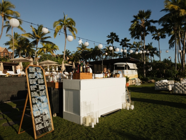 A white countertop bar with white candles sitting on the ground, and lantern lights above the bar.