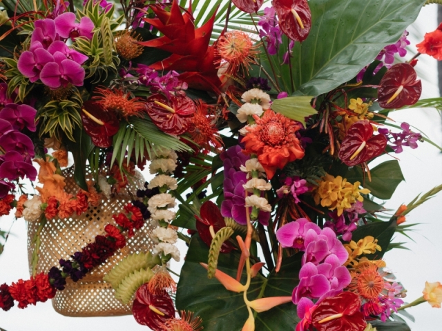 Close up of a floral display at an event with bright Hawaiian flowers and foliage.