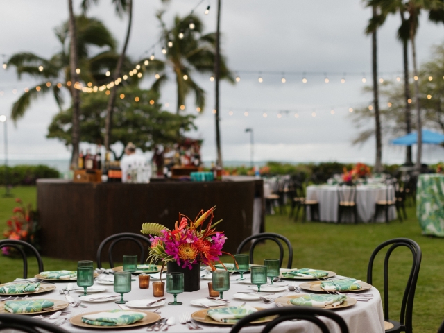 Round table with green and white napkins, green glasses, and colorful floral centerpiece.