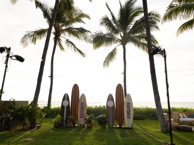 Multiple surfboards lined up at an outdoor event with client logo printed on the board.