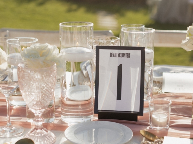 Place setting with gold silverware, white plates, champagne table runner, and framed table