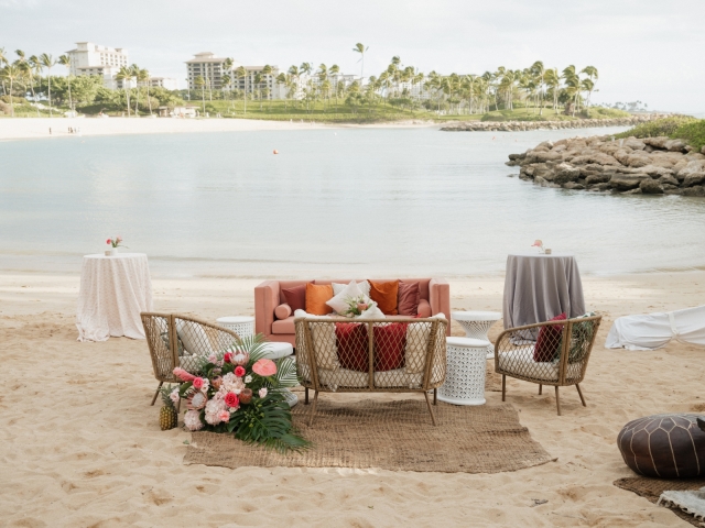 Lounge area with couch and chairs overlooking beach in Hawaii.