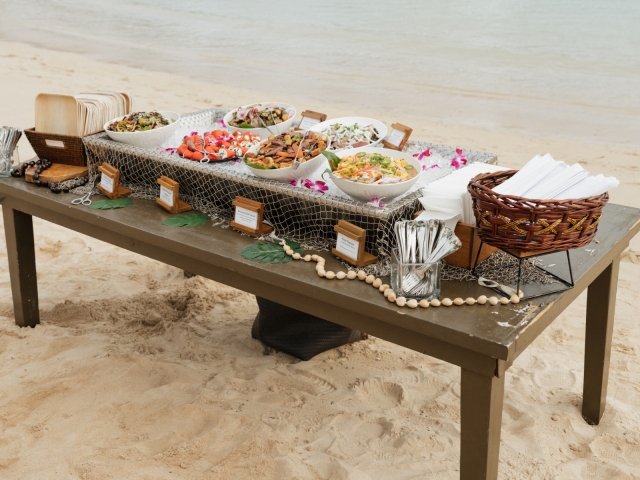 Food set up on a dark brown table overlooking the water.