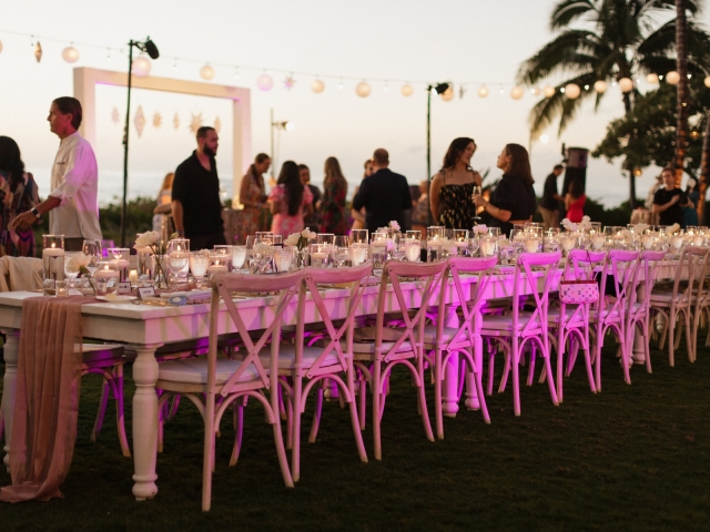 Long wooden table at night with lantern lights in Hawaii.