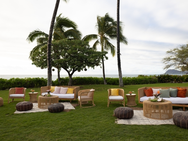 A view of multiple lounge areas at an outdoor event overlooking the ocean.