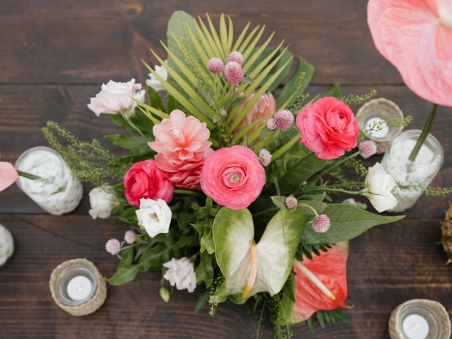 Close up of a floral centerpiece with coral and tropical flowers.