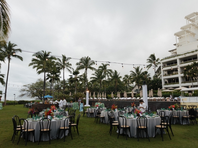 Outdoor event space at Four Seasons in Hawaii  with round tables, wooden chairs, and overhead led lights.